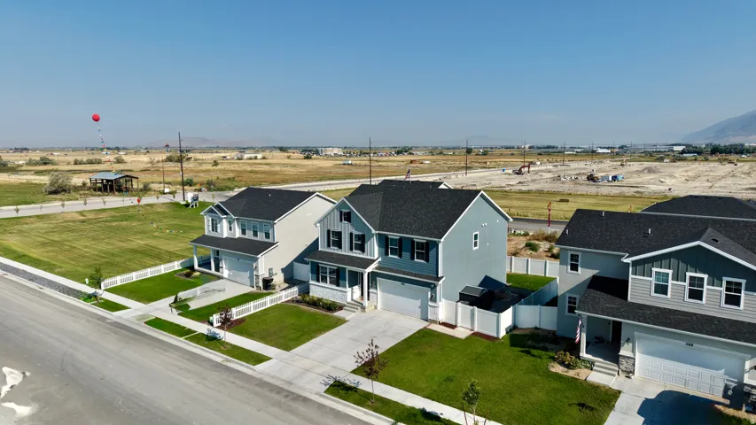 Modern two-story residence with light blue exterior, black asphalt shingles, and two-car garage