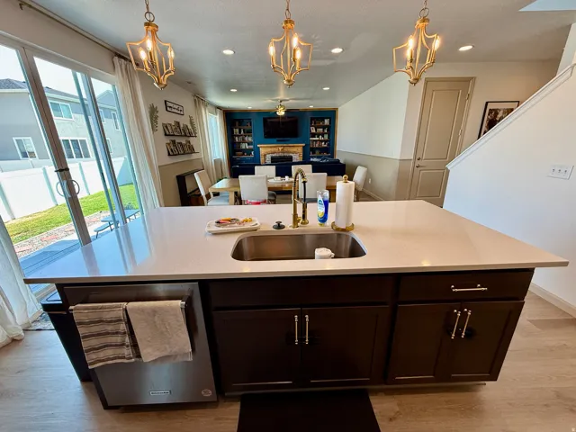 Chef's kitchen island featuring quartz countertop, undermount sink with integrated prep space, and dark cabinetry with chrome hardware