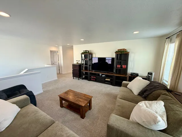 Spacious recreation room featuring neutral carpet flooring, recessed ceiling lighting, and abundant natural light from multiple windows