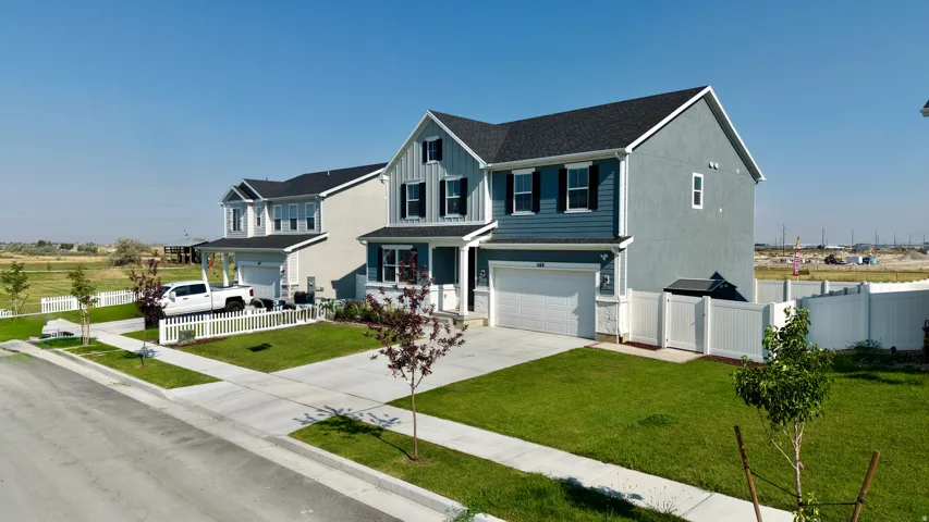 Modern two-story home featuring a light blue and white exterior with peaked gable rooflines, double-hung windows with dark trim, and a two-car garage with a gray door