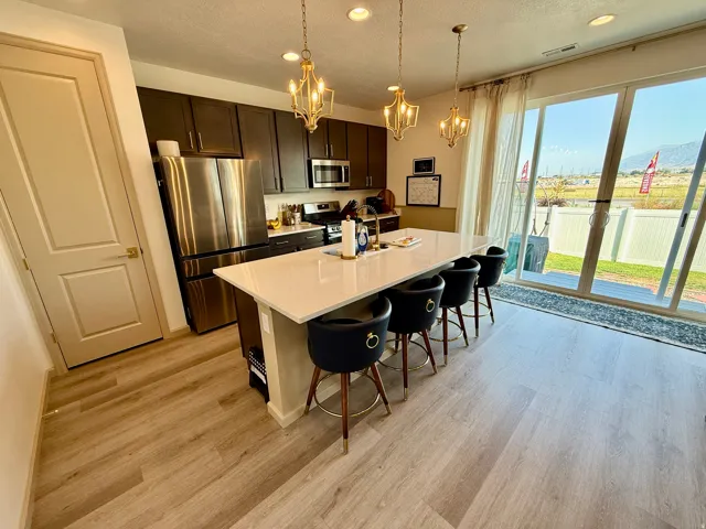 Kitchen featuring dark wood cabinetry, stainless steel appliances, a white island with seating, and wood-finish flooring