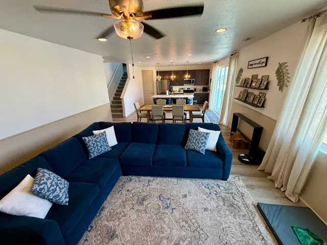 Open-concept living space featuring wood-finish flooring, recessed lighting, a modern ceiling fan, and a staircase with carpeted treads