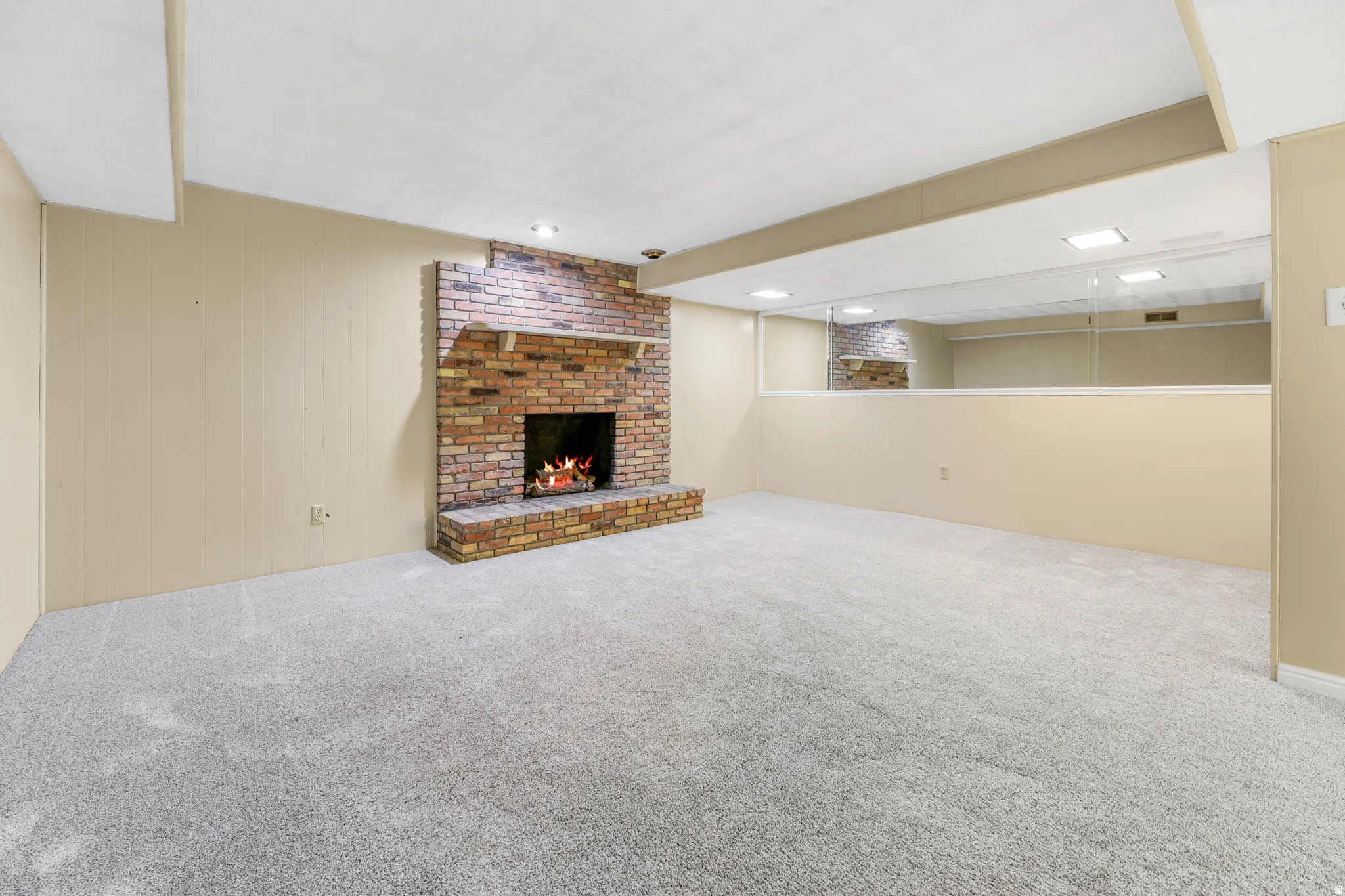 Brick fireplace with a hearth, recessed lighting, and carpeted flooring