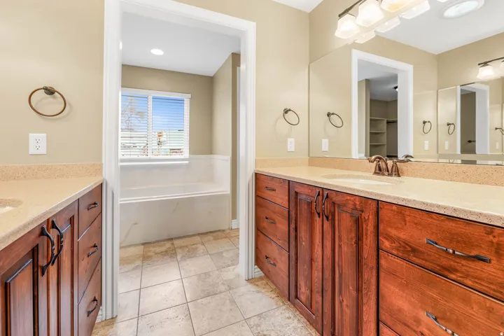 Dual wood-finish vanities with light-toned countertops and integrated sinks