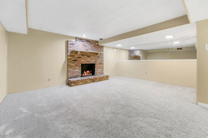 Brick fireplace with a hearth, recessed lighting, and carpeted flooring