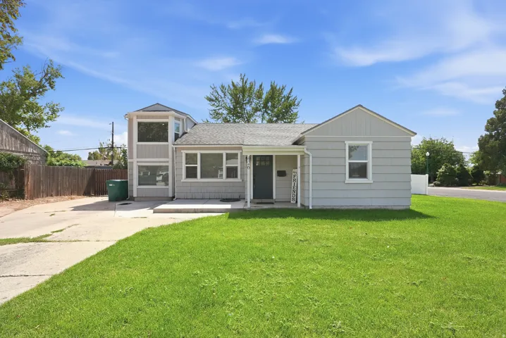 Two-story residence featuring light gray siding with white trim, a covered front entry, an attached two-story bay window structure, a concrete driveway, and a front lawn