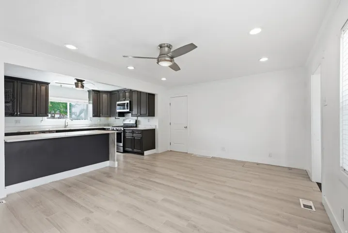 Kitchen with dark wood-finish cabinetry, light-toned countertops, and a stainless steel oven/range