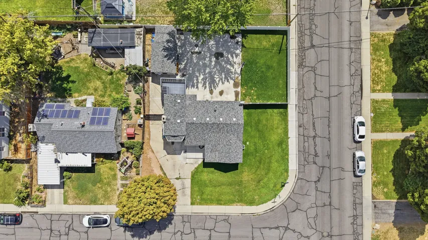 Property featuring a shingled roof, solar panel array, and a spacious front lawn