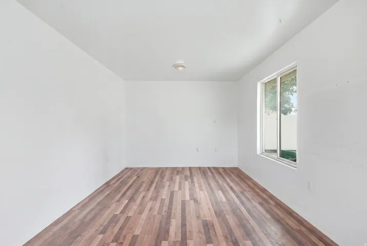 Wood-finish flooring, white walls, flush-mount ceiling light, and a sliding window
