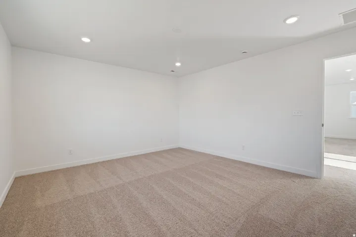 Spacious bedroom with neutral wall finishes, recessed ceiling lighting, and plush carpeting throughout