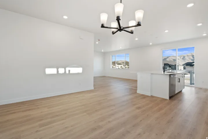 Spacious room featuring wood-finish flooring, a modern chandelier, recessed lighting, and large windows with mountain scenery