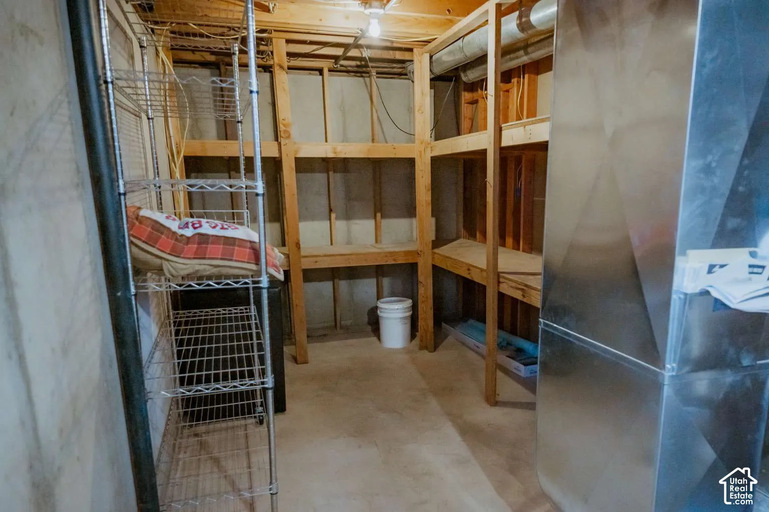 Utility space featuring exposed wood-frame wall construction, custom-built wooden storage shelving, and exposed galvanized metal ductwork