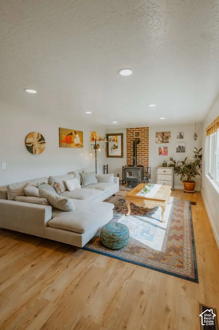 Living area featuring wood-finish flooring, recessed lighting, and a brick-surround wood-burning stove