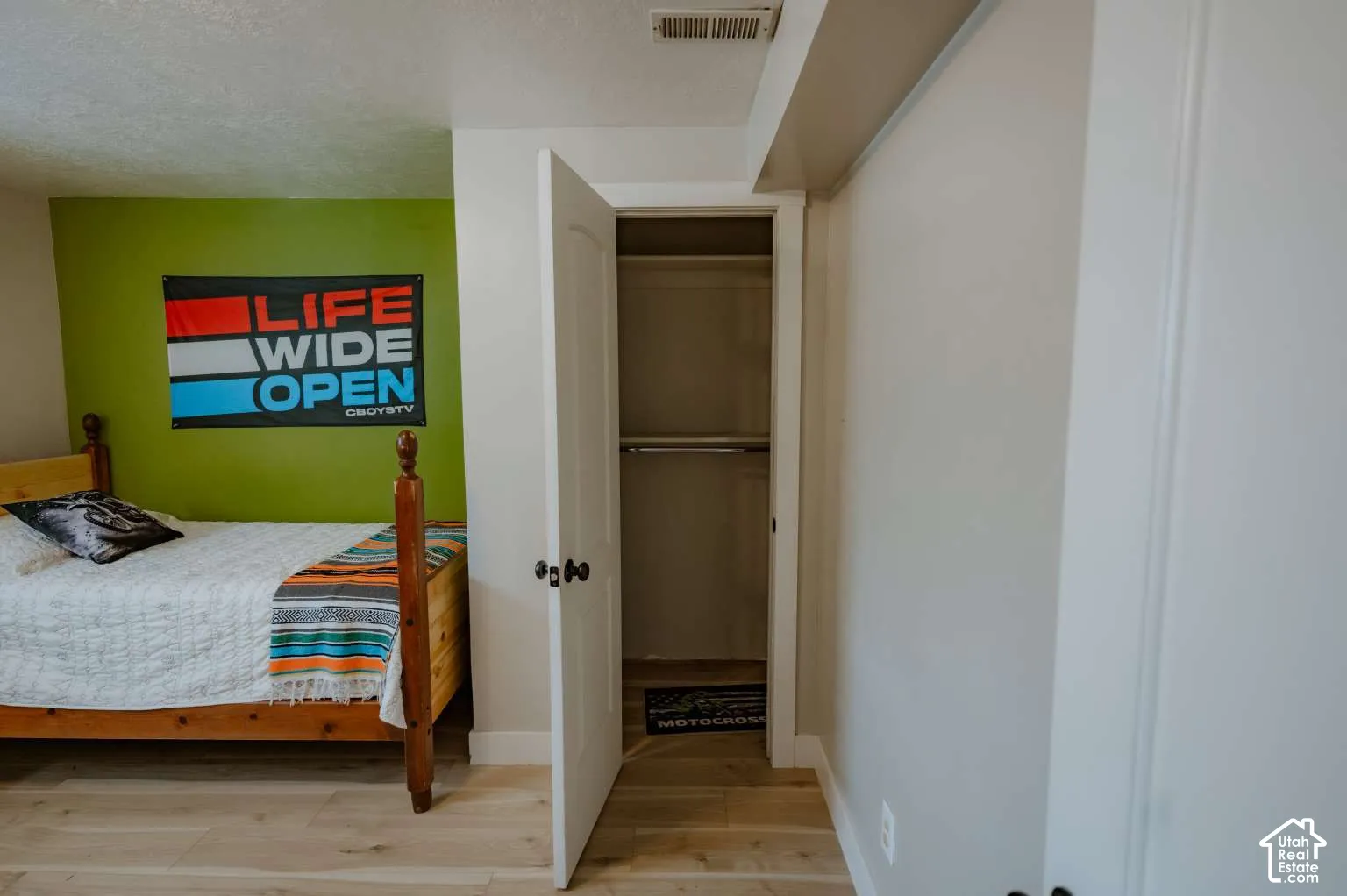 Room interior featuring wood-finish flooring, a reach-in closet with an arched two-panel door, and matte black hardware