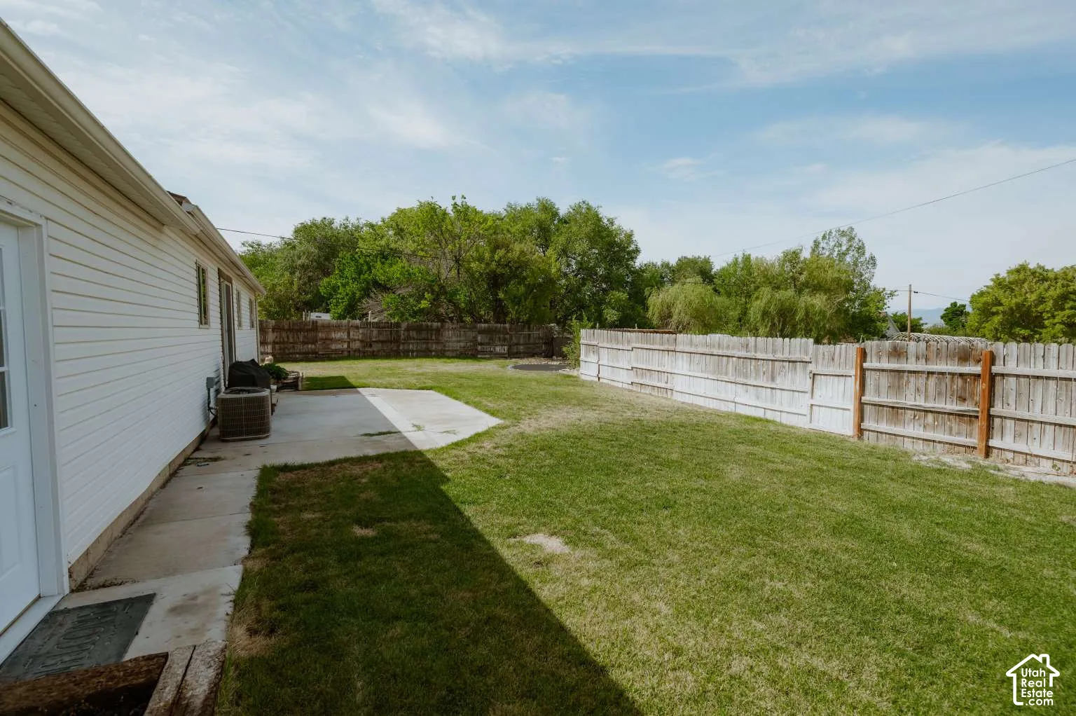 Backyard featuring a concrete patio, lawn, and perimeter wood fencing