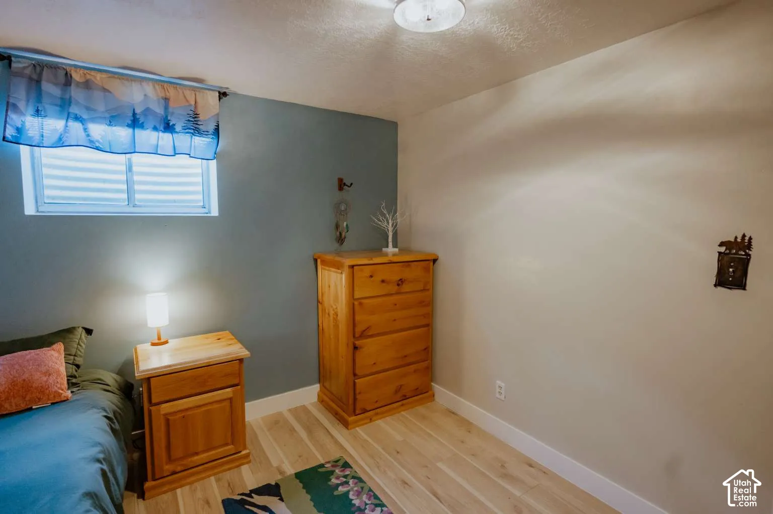 Neutral-toned room featuring wood-finish flooring, a horizontal slider window, and a dual-tone wall finish