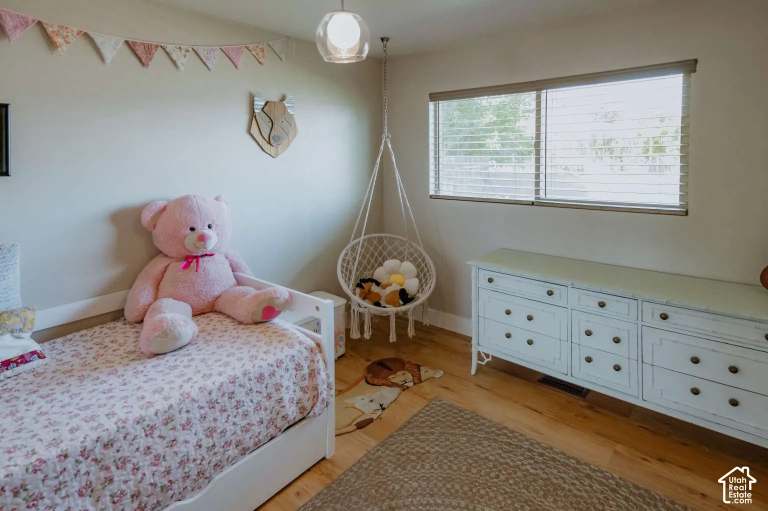 Neutral-toned room featuring wide-plank wood-finish flooring, a large horizontal window with integrated blinds, and a glass-globe pendant light fixture