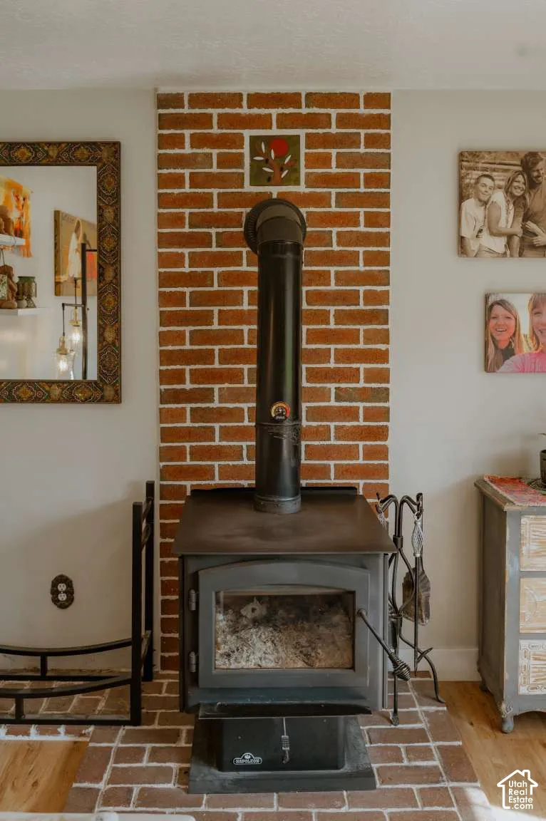 Freestanding metal stove featuring a chimney pipe and a brick-accented hearth