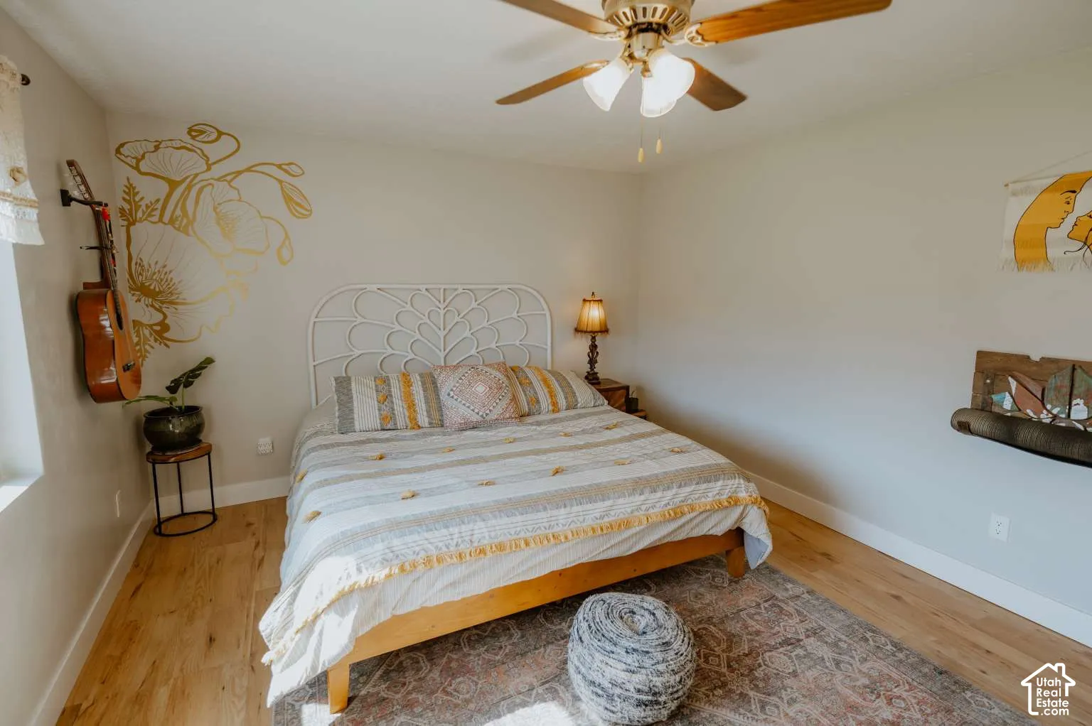 Wood-finish flooring, neutral wall tones, and a multi-blade ceiling fan with integrated lighting