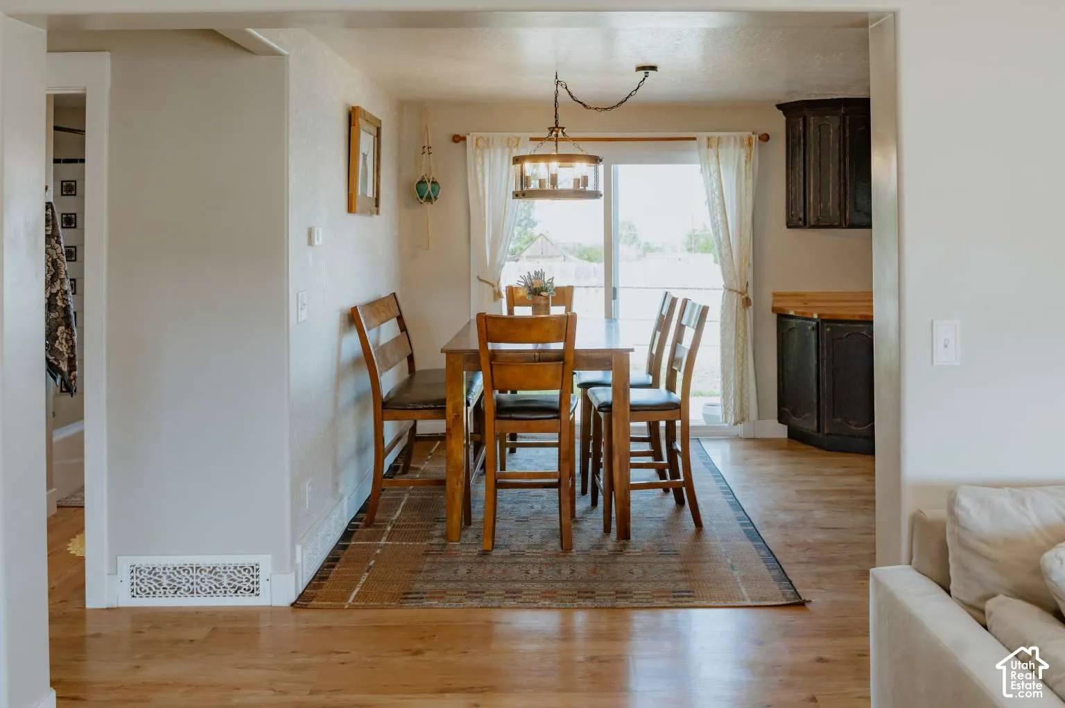 Wood-finish flooring, sliding glass door, pendant light fixture, and dark-toned built-in cabinetry