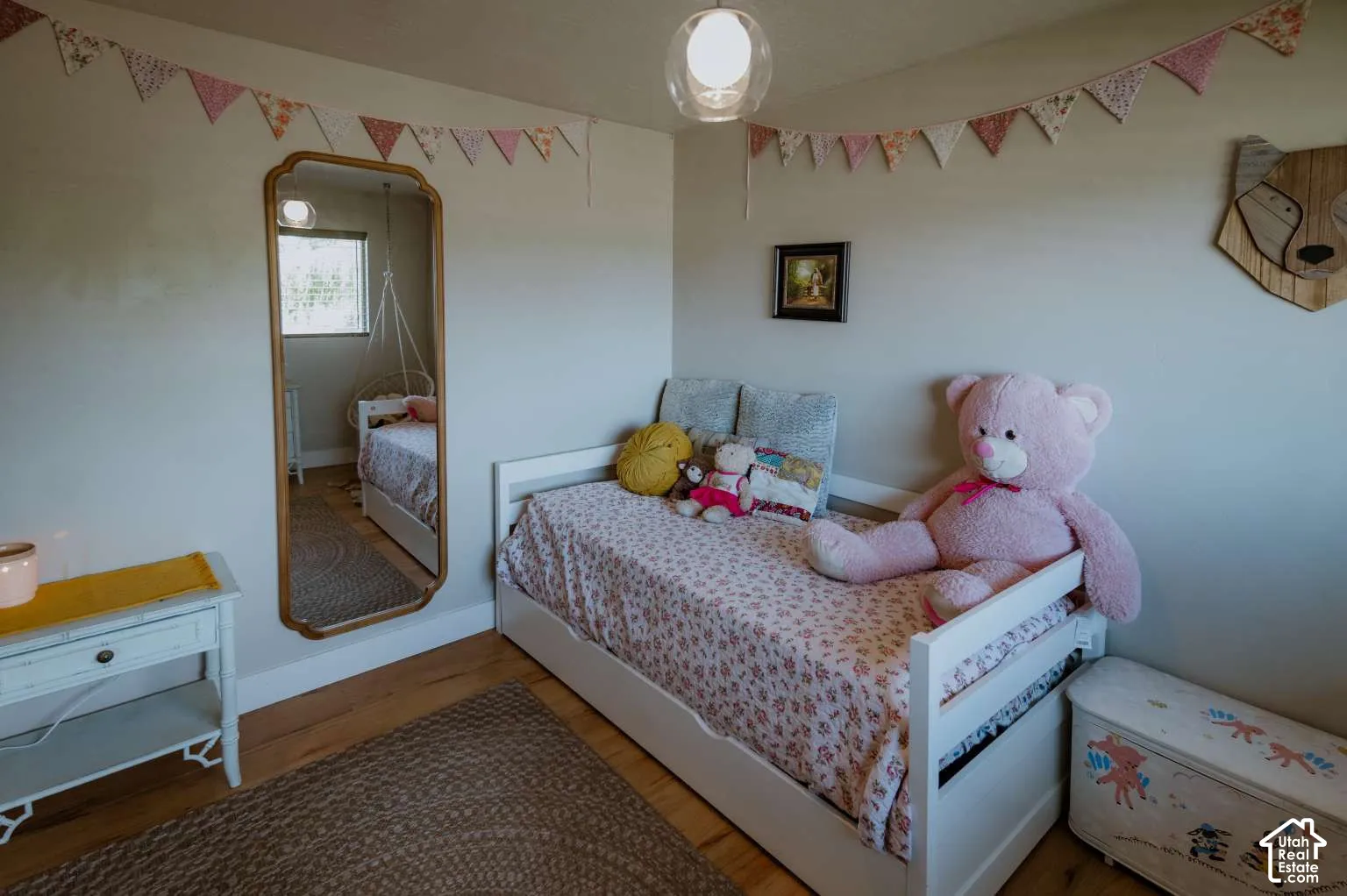 Room featuring wood-finish flooring, a wall-mounted arched mirror with a gold-tone frame, and a globe-style pendant light fixture