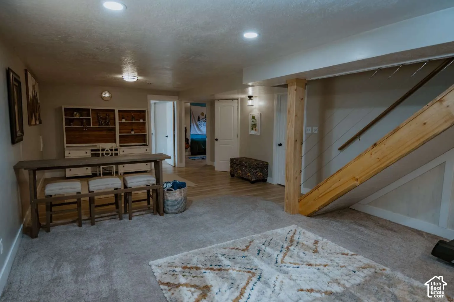 Built-in cabinetry with integrated desk space, wood-finish flooring, recessed lighting, and a staircase featuring a natural wood support post with cable railing