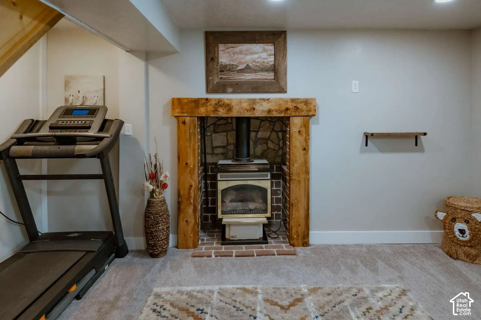 Freestanding stove with a rustic timber mantel, stone-accented hearth, brick firebox, and neutral wall-to-wall carpeting