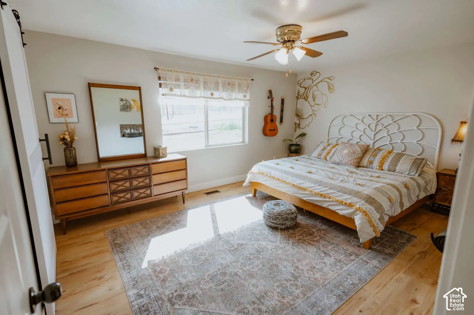 Bedroom featuring wood-finish flooring, a ceiling fan with integrated lighting, and a sliding barn-style door