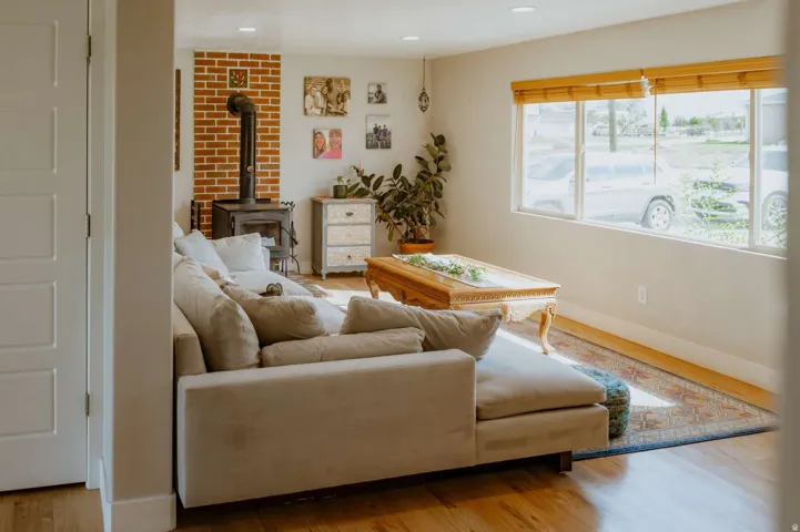 Hardwood flooring, brick accent wall with stove, large windows, recessed lighting, and a white paneled door