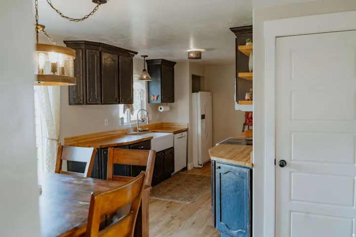 Kitchen featuring dark cabinetry, natural wood-finish countertops, and a white farmhouse sink