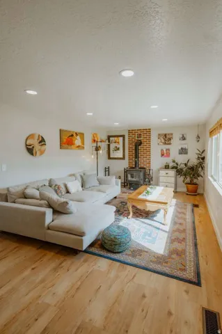 Wood-finish flooring throughout, recessed lighting, brick accent wall, and a window with natural light
