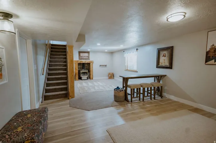 Finished lower level with recessed lighting, wood-finish flooring, and a wood-burning stove with a stone surround