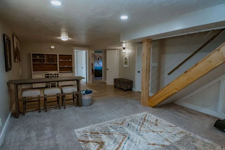 Recessed ceiling lighting, wood-finish flooring, carpeted floor, built-in shelving, and a wood-finish staircase