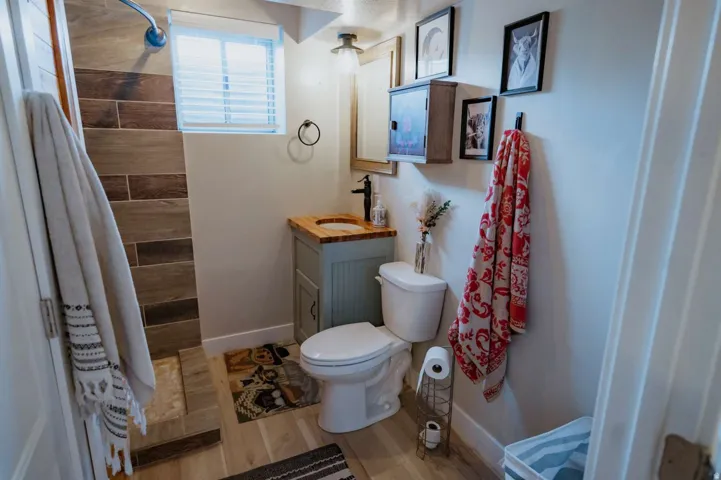 Wood-look tile shower surround with a fixed showerhead and window with blinds