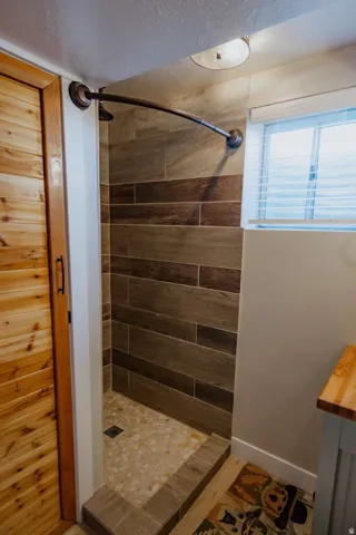 Wood-look tile shower walls and a pebble-tiled shower pan