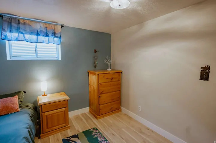 Wood-finish flooring with crisp white trim, a fixed window with horizontal blinds, and a neutral wall color