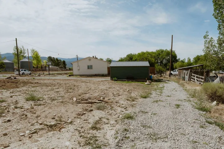 Gravel driveway leading to a detached storage building with a metal roof