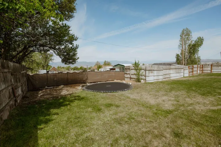 Expansive backyard featuring a partial wood fence, partial privacy screening, and mature trees