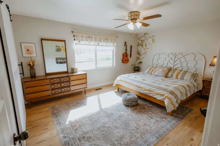 Light wood-finish flooring with a ceiling fan and overhead lighting