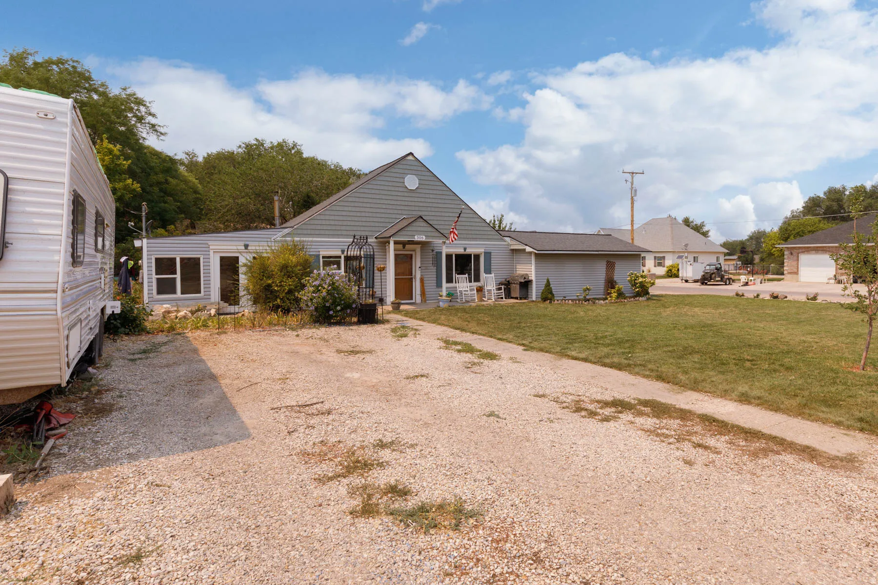 Spacious rural property featuring a single-story residence with siding exterior, pitched roof design, and multiple outbuildings