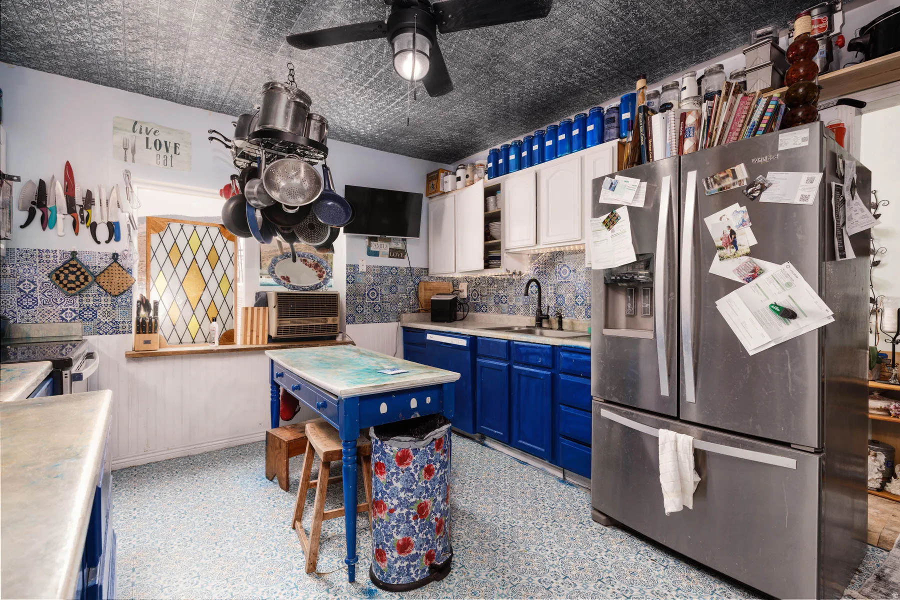 Vibrant kitchen featuring rich blue cabinetry, stainless steel refrigerator, and a central island with wood-finish seating