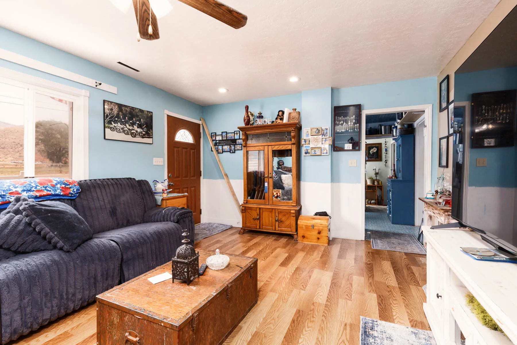 Wood-finish flooring, ceiling fan, recessed lighting, white trim, and a paneled door with an arched window