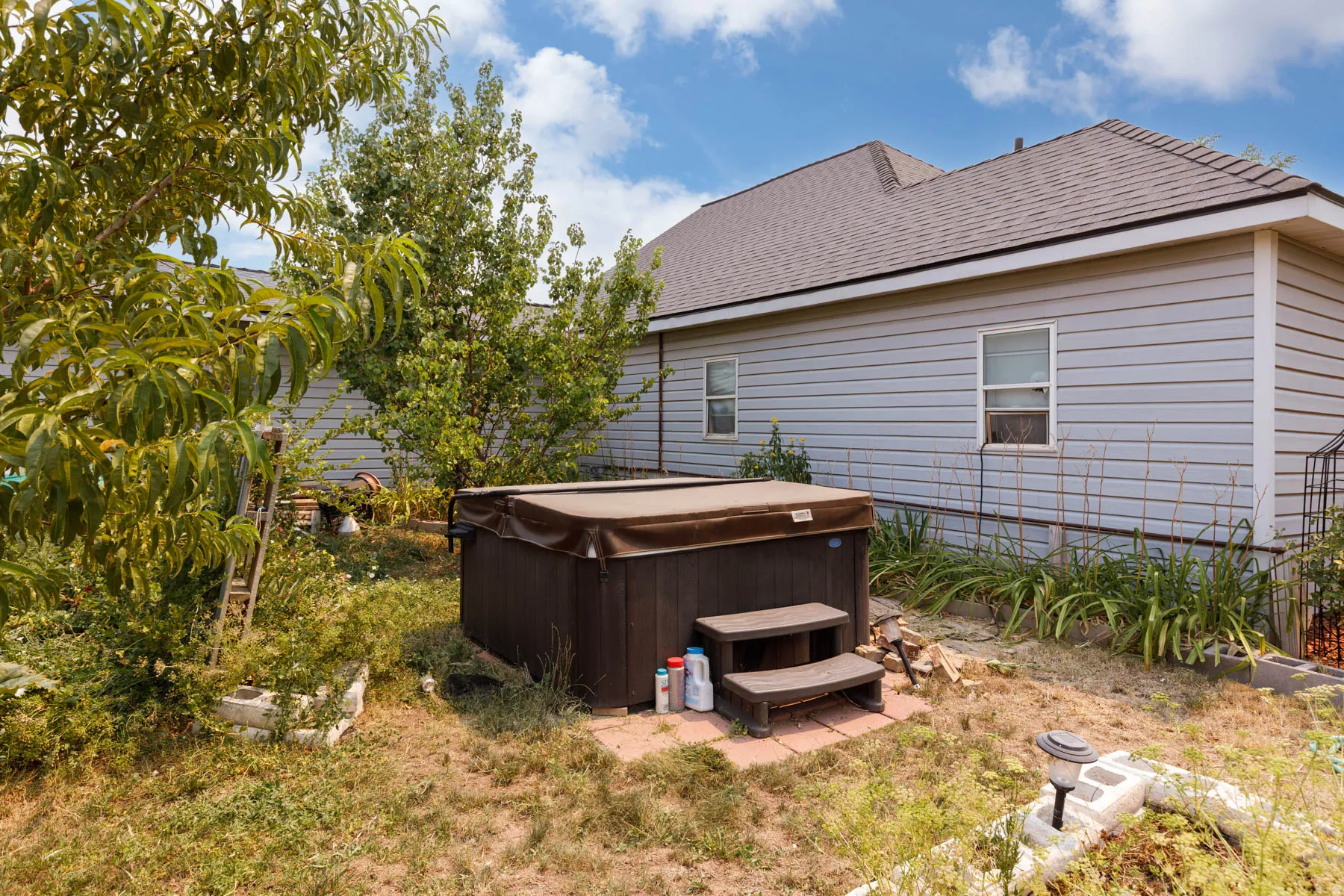 Backyard featuring a covered hot tub with steps, light blue siding, and a brown shingle roof