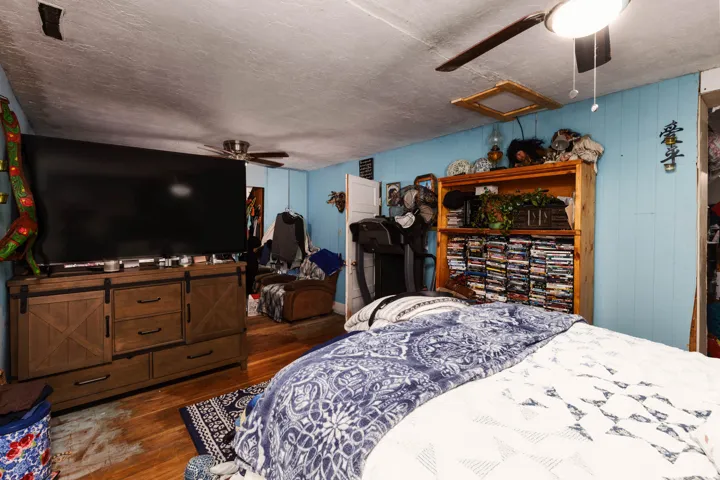 Wood-finish flooring, ceiling fan, wood-paneled walls, built-in shelving, and recessed ceiling fixture