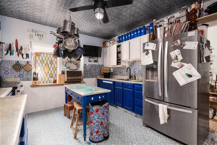 Vibrant kitchen featuring rich blue cabinetry, stainless steel refrigerator, and a central island with wood-finish seating
