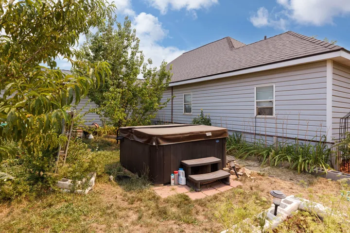Backyard featuring a covered hot tub with steps, light blue siding, and a brown shingle roof