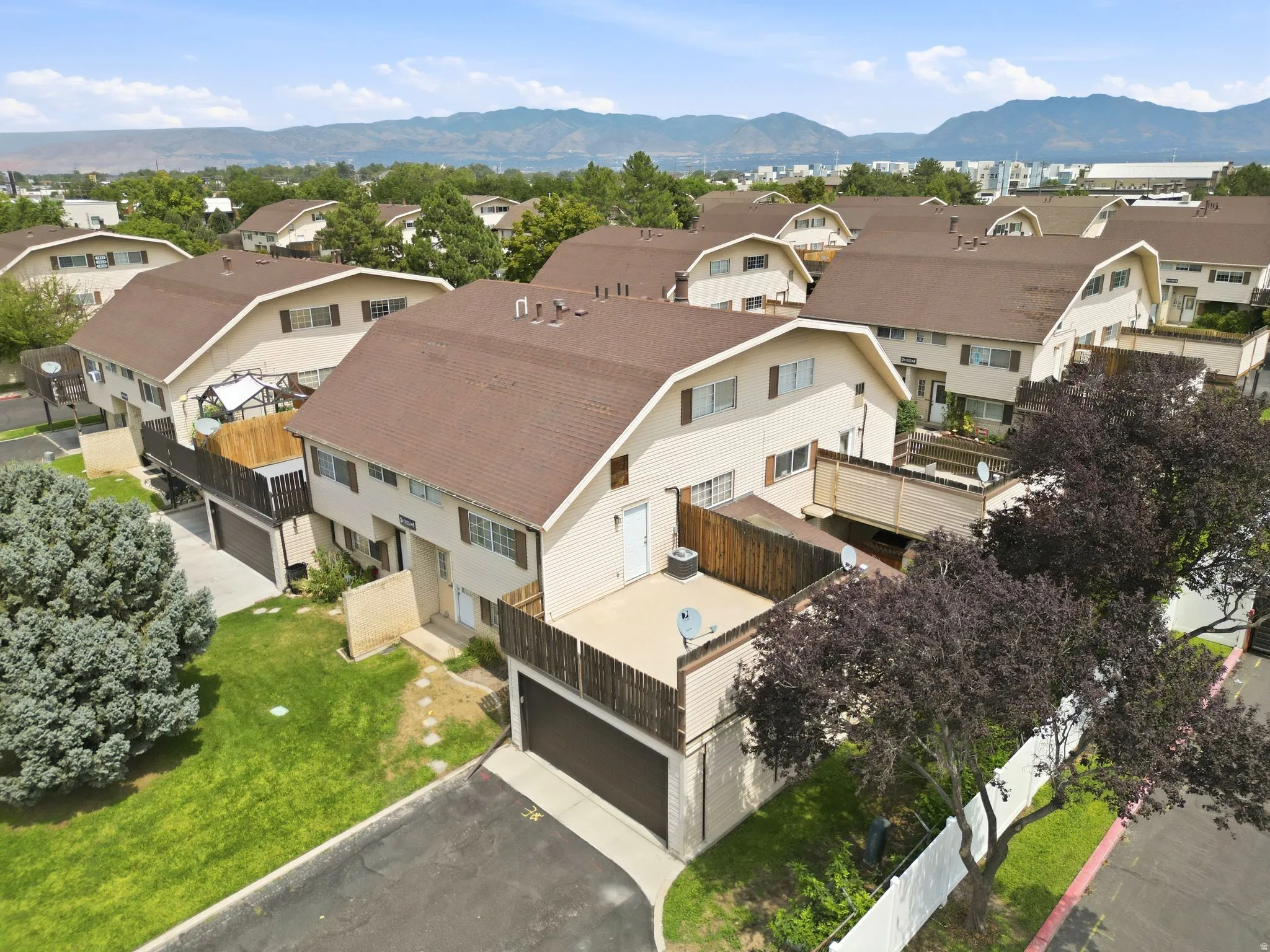 Townhouse-style residences featuring brown shingle roofs, balconies with wood railings, and individual garage access
