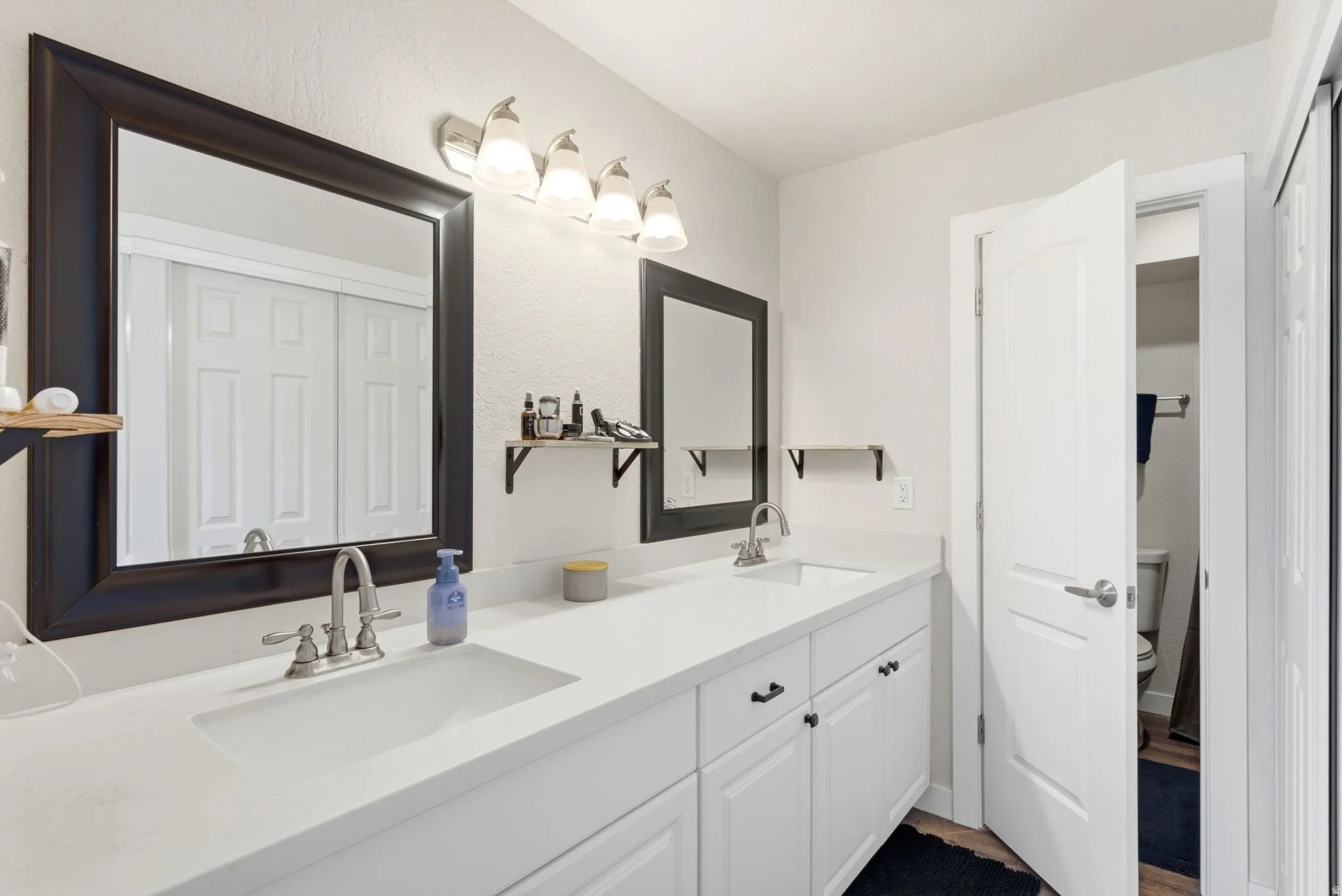 Dual undermount sinks with brushed nickel fixtures, white cabinetry, and a light-toned countertop