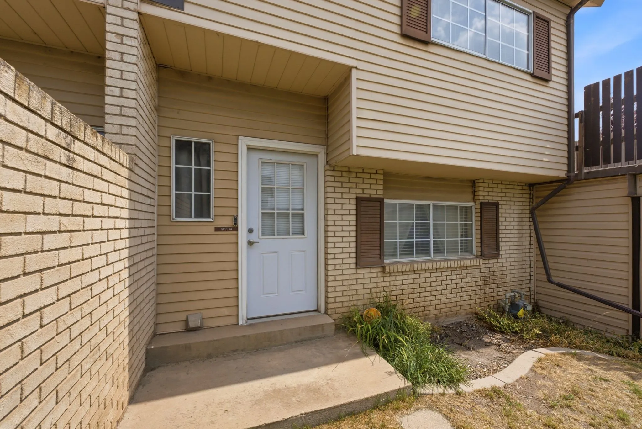 Brick and siding exterior with a covered entry featuring a white paneled door and transom window
