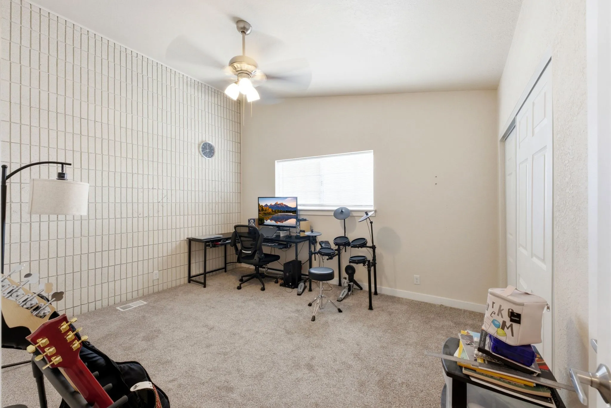 Versatile bonus room featuring tile accent wall, carpet flooring, ceiling fan with integrated lighting, and abundant natural light from large window